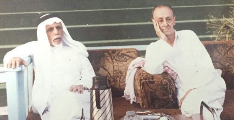حسين سرحان جالسًا إلى جوار أحد معارفه في صورة أرشيفية
